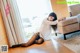 A woman sitting on the floor in a white shirt and black stockings.