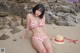 A woman in a red and white bikini sitting on a beach.