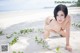 A woman in a black bikini laying on a sandy beach.