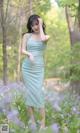 A woman in a blue dress standing in a field of flowers.