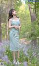 A woman in a blue dress standing in a field of flowers.