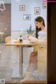 A woman sitting at a table with a cup of coffee.