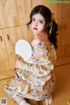 A woman in a kimono sitting on the floor holding a fan.