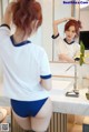 A woman in a white shirt and blue panties standing in front of a mirror.