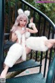 A woman in a white fur outfit sitting on a set of stairs.