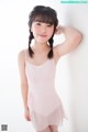 A young girl in a pink leotard posing for a picture.