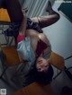 A woman laying on top of a desk in a classroom.