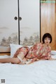 A woman in a kimono laying on a bed.