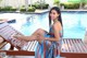 A woman sitting on a wooden bench next to a swimming pool.