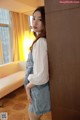 A woman leaning against a wooden cabinet in a room.