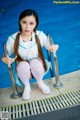 A woman sitting on the edge of a swimming pool.