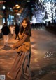 A woman standing in the middle of a street at night.