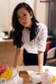 A woman in a white shirt and black skirt holding a bowl of fruit.