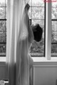 A pregnant woman standing in front of a window.