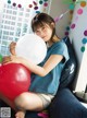 A young woman sitting on a couch holding a large balloon.