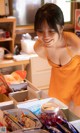 A woman in an orange shirt is looking at a box of food.