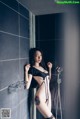 A woman in a black lingerie standing in a shower.