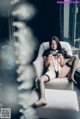 A woman sitting on a white chair in a black lingerie.