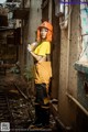 A woman in a yellow and black outfit standing in an abandoned building.