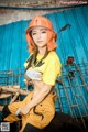 A woman in a yellow shirt and orange hard hat posing for a picture.