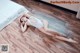 A woman laying on the floor in a white bathing suit.