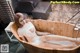 A woman is sitting in a wooden bathtub filled with foam.