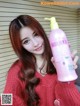 A woman holding a bottle of shampoo in her hand.