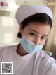 A woman wearing a surgical mask in a hospital room.