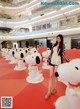 A woman standing in front of a row of snoopy statues.