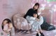 A couple of women sitting on top of a pink couch.