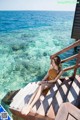 A woman sitting on a wooden deck overlooking the ocean.