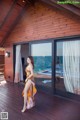 A woman standing on a wooden deck next to a sliding glass door.