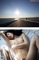 A naked woman laying on a bed next to the ocean.