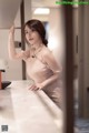 A woman in a pink dress leaning on a counter.