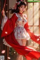 A woman in a red and white dress holding a red umbrella.