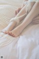 A woman is sitting on a bed with her legs crossed.