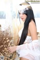 A woman in a white lingerie standing next to a bunch of dry grass.