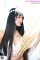 A woman with long black hair holding a bunch of wheat.