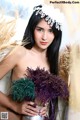 A naked woman holding a bunch of dried flowers.