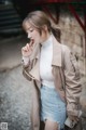 A woman in a white turtle neck sweater and a beige trench coat.