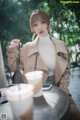 A woman sitting at a table with a cup of coffee.