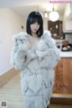 A woman in a fur coat standing in a kitchen.