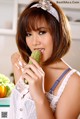 A woman holding a cucumber in front of her mouth.