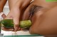 A woman is holding a cucumber in her hand.