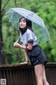 A woman in a school uniform holding an umbrella.