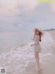 A woman standing on a beach next to the ocean.