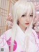 A woman with long white hair wearing a pink kimono.