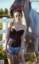 A woman standing next to a white horse in a field.