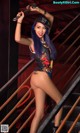 A woman with blue hair is posing on a set of stairs.