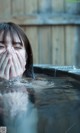 A woman covering her face with her hands in the water.